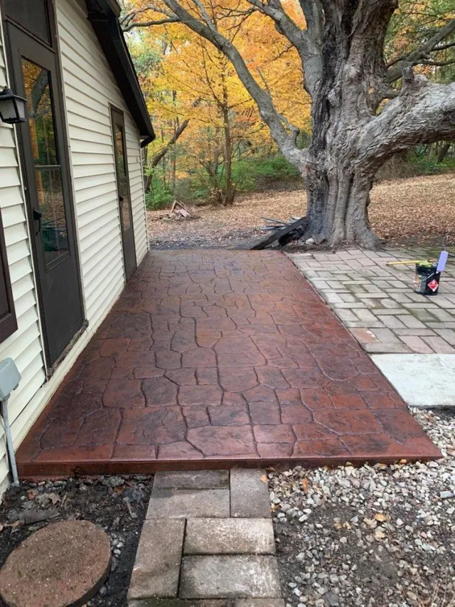 Decorative and colored concrete patio installed outside backdoor home in Gahanna with large oak tree
