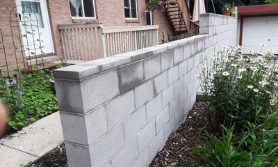 Retaining wall concrete styled as brick with flowers separating one property from another