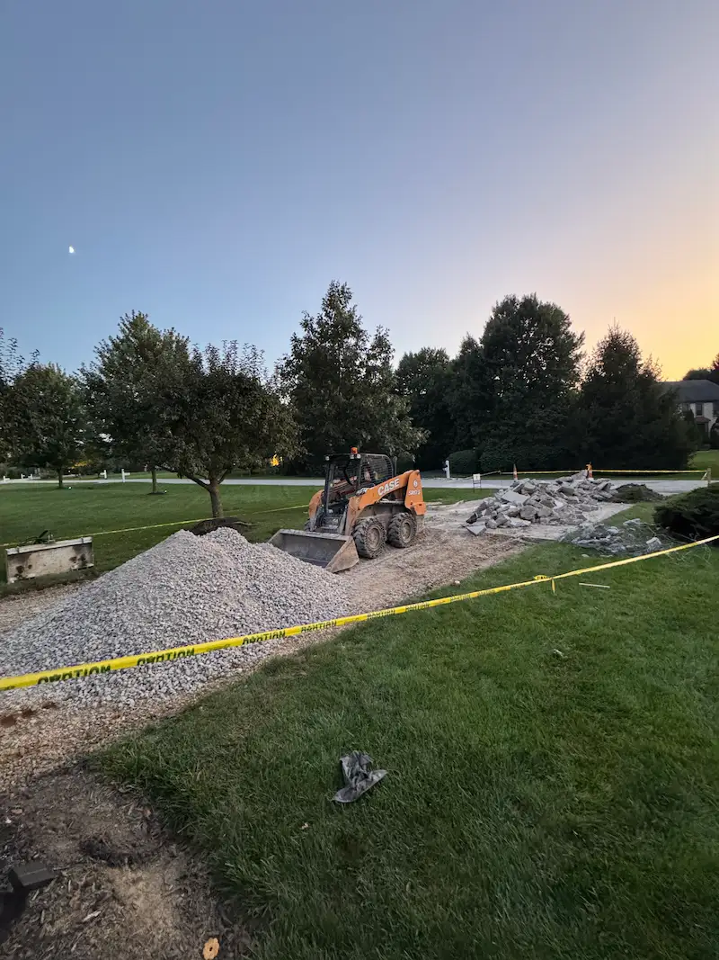 Excavator removing old concrete driveway and prepping for new concrete driveway installation