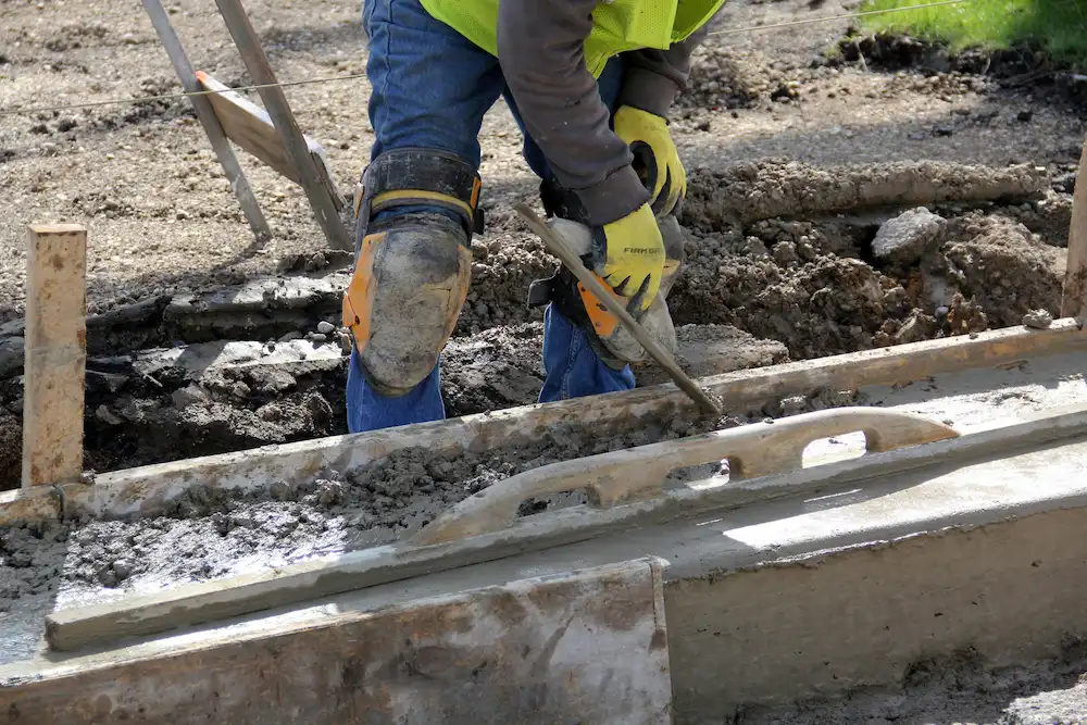 Worker pouring cement during concrete driveway installation