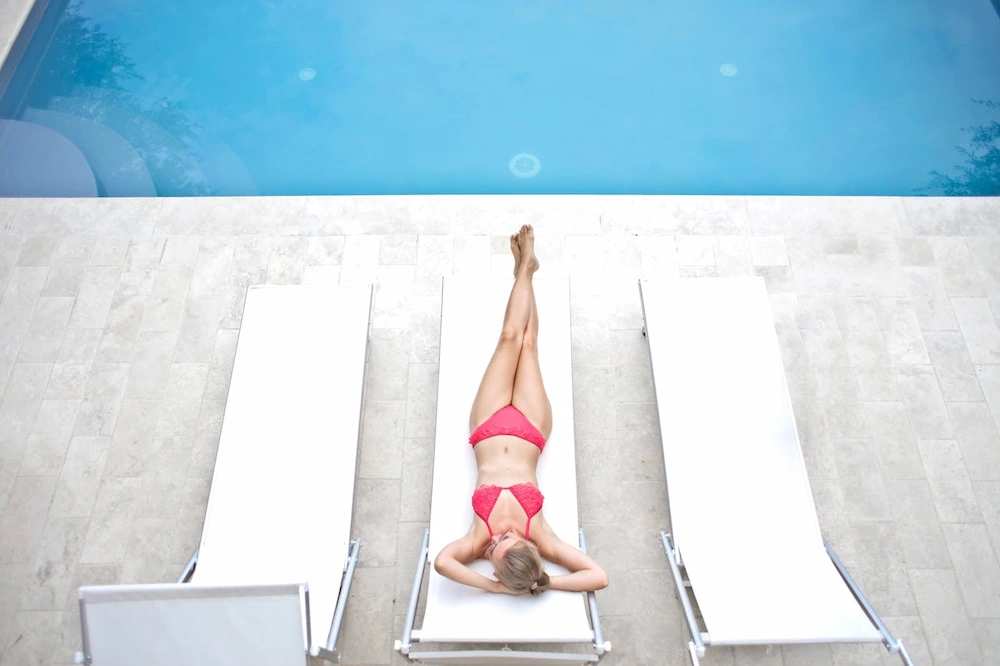 Woman relaxing beside concrete pool deck area